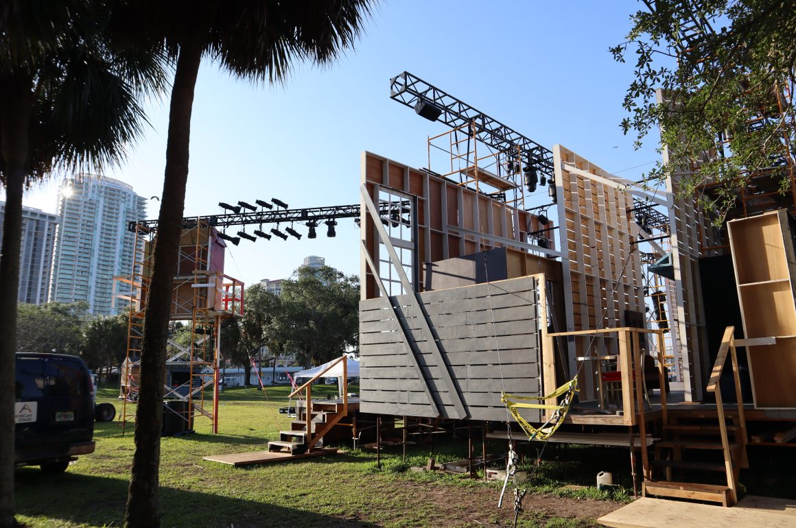 A photo of a large outdoor stage under construction with a palm tree in the foreground.